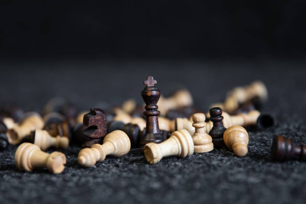 Scattered chess pieces on a blurred black background.